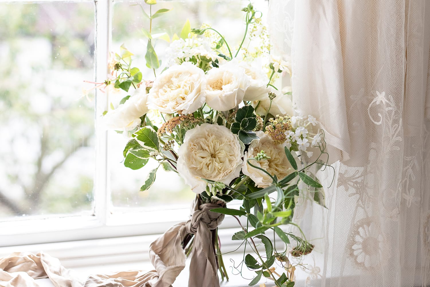 Ramo de boda de rosas crema paciencia en el alféizar de la ventana
