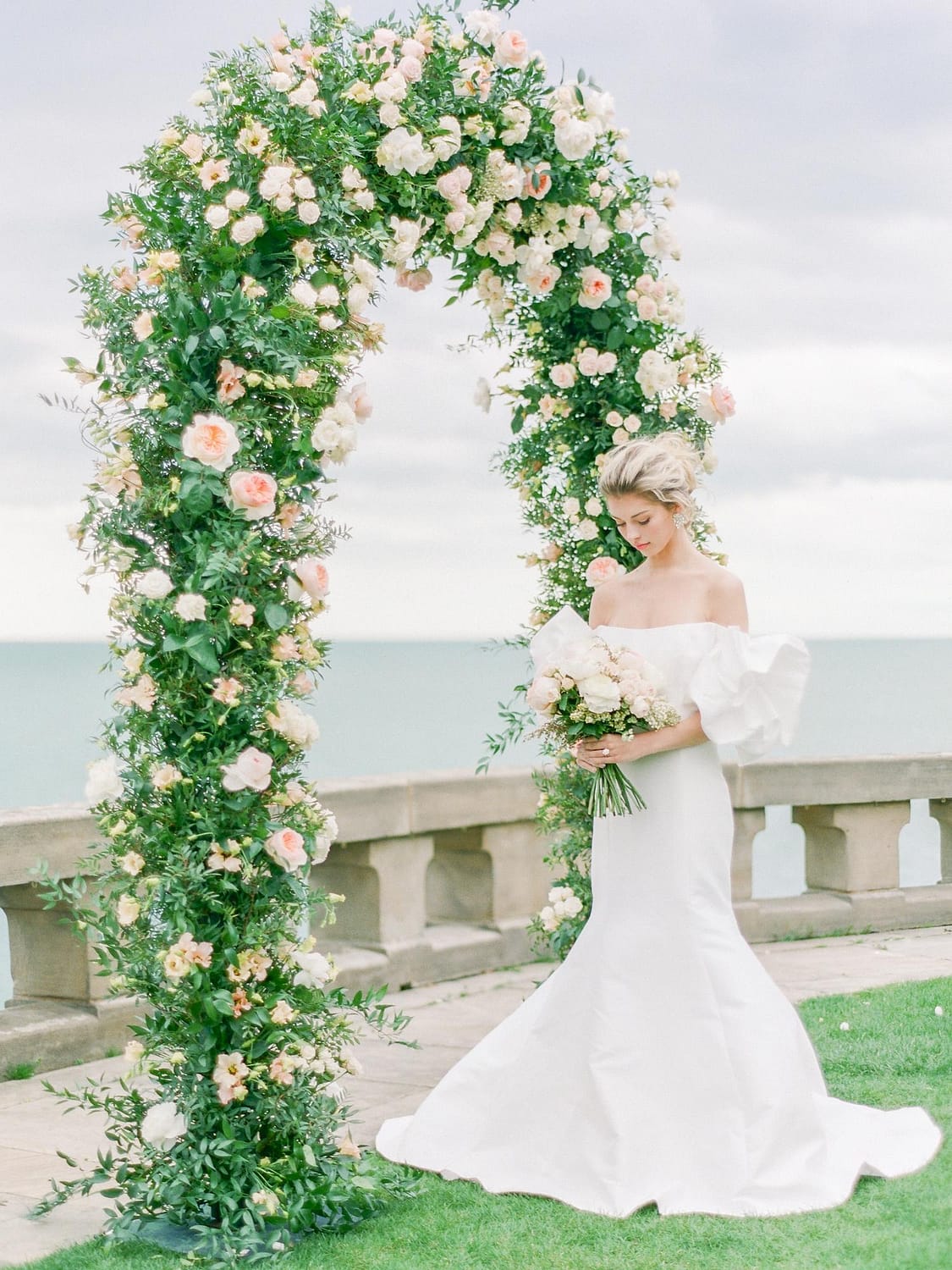 Braut mit Blumenhochzeitsbogen und Brautstrauß