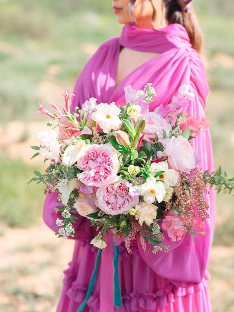 العروس مع زهور الزفاف ترتدي فستان الزفاف الوردي