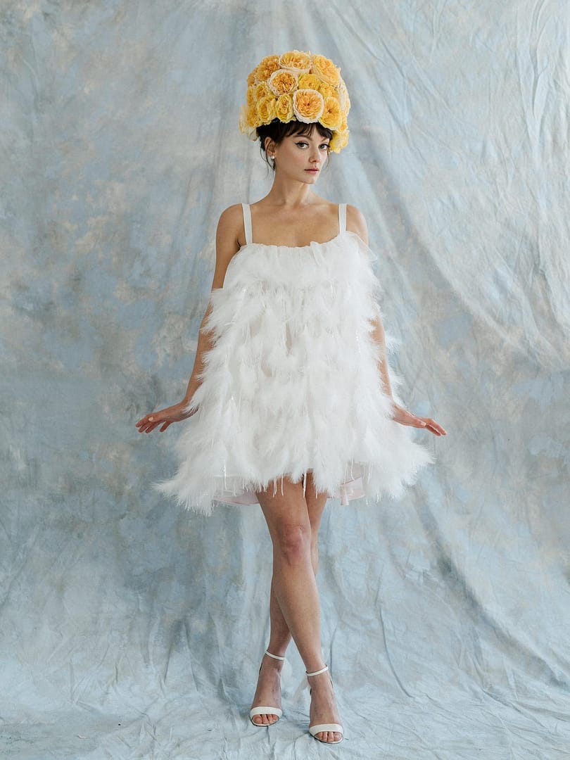 Robe de mariée blanche avec plumes et chapeau rose